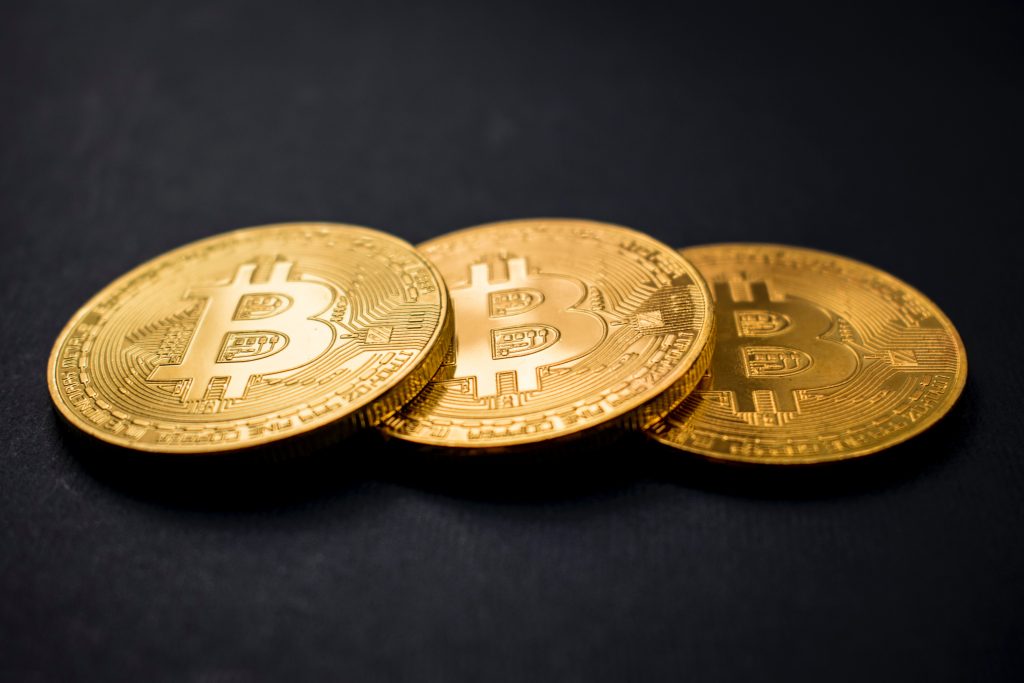 bitcoins สีทองสามอันจัดเรียงตามแนวทแยงมุมบนพื้นหลังสีดำ